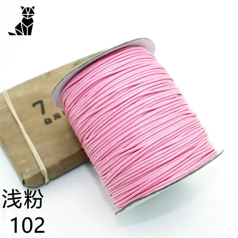 Gros plan sur une bobine de fil rose à côté d’une boîte pour le bracelet personnalisé de photos d’animaux
