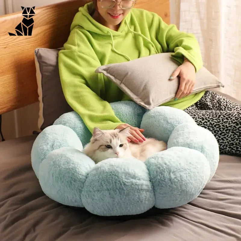 Femme assise sur le lit avec son chat à côté du Super Soft Washable Flower Cushion for Cats, Fleurs Lavable super